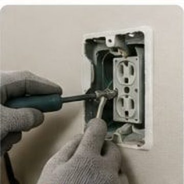 Electrician wiring a wall outlet box